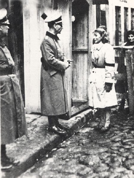 A Jewish woman being investigated by a Gestapo man during an Aktion in the Vilnius ghetto.